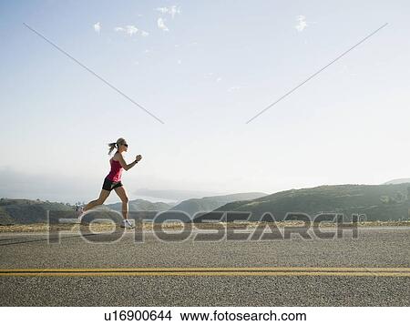 Picture - Runner training on the side of the road. Fotosearch