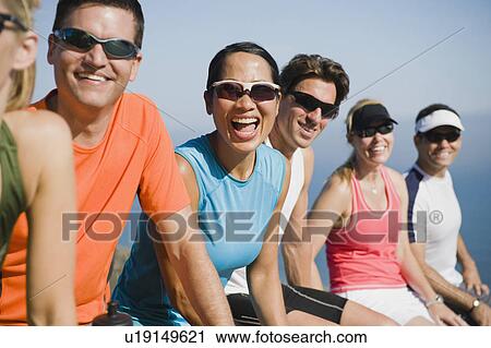 Stock Image - Runners resting on the side of the road. Fotosearch