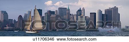 Stock Photograph - Sailboat on river in front of Lower Manhattan. Fotosearch