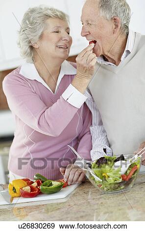 Stock Photo - Senior couple preparing salad together. Fotosearch