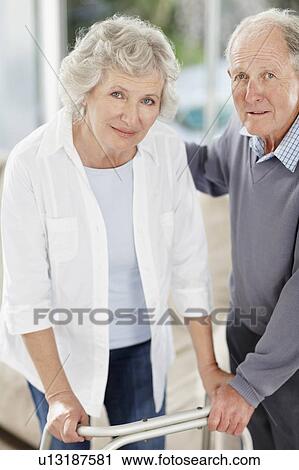 Senior man assisting woman with a walker View Large Photo Image Stock Image - Senior man assisting woman with a walker. Fotosearch