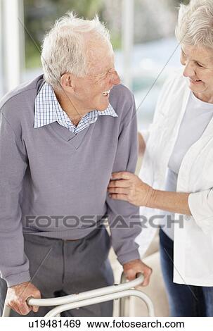 Stock Photo - Senior woman assisting man with a walker. Fotosearch