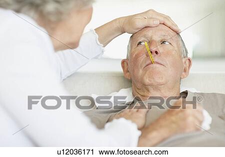 Senior woman caring for man with a fever View Large Photo Image Stock Image - Senior woman caring for man with a fever. Fotosearch