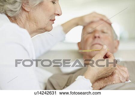 Stock Image - Senior woman caring for man with a fever. Fotosearch