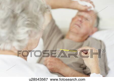 Stock Photo - Senior woman caring for man with a fever. Fotosearch