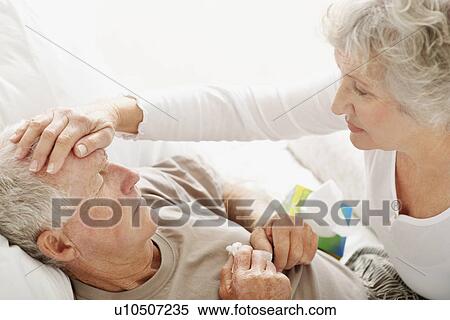 Stock Photography - Senior woman caring for man with a fever. Fotosearch
