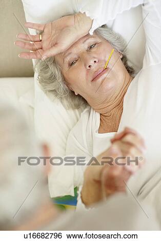 Stock Photograph - Senior woman with a thermometer in her mouth. Fotosearch