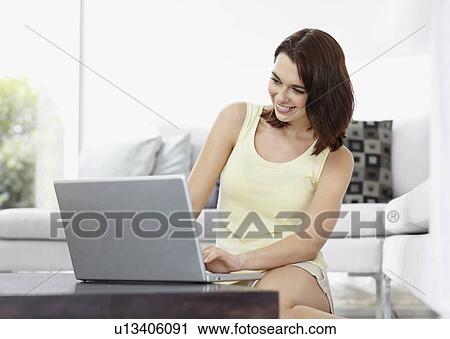 Stock Image - Smiling brunette woman browsing the internet. Fotosearch