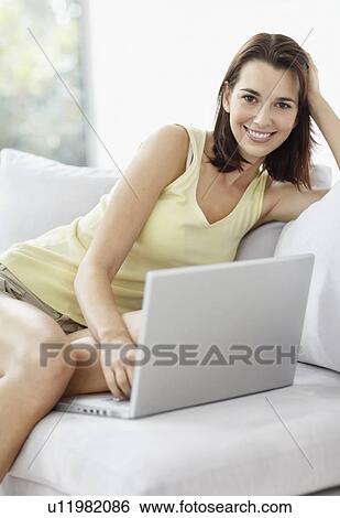 Stock Photograph - Smiling brunette woman browsing the internet. Fotosearch