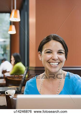 Stock Photograph - Smiling woman sitting at table in restaurant. Fotosearch