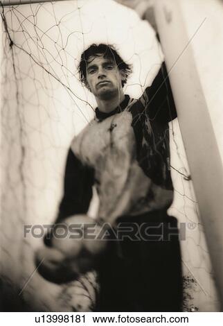 Stock Image - Soccer player standing behind net. Fotosearch