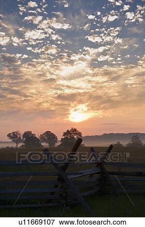 Stock Photo - Sunrise over rustic fence. Fotosearch