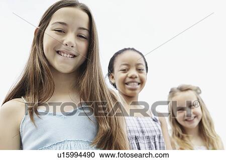 Stock Image - Three girls standing in a row. Fotosearch