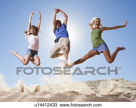 Three people jumping in the sand View Large Photo Image Stock Image - Three people jumping in the sand. Fotosearch