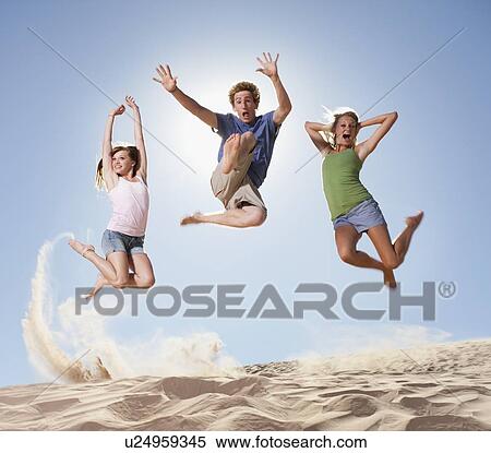 Stock Photography - Three people jumping in the sand. Fotosearch