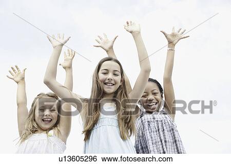 Three young girls with their arms raised View Large Photo Image Stock Photograph - Three young girls with their arms raised. Fotosearch