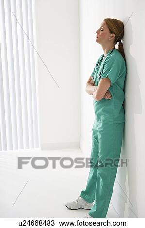 Stock Image - Tired healthcare worker leaning against wall. Fotosearch
