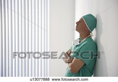 Tired healthcare worker leaning against wall View Large Photo Image Stock Photo - Tired healthcare worker leaning against wall. Fotosearch