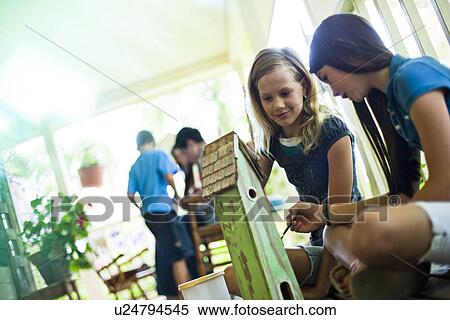 Stock Photography - Two girls painting a birdhouse. Fotosearch