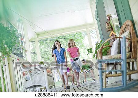 Stock Image - Two young girls walking on porch. Fotosearch