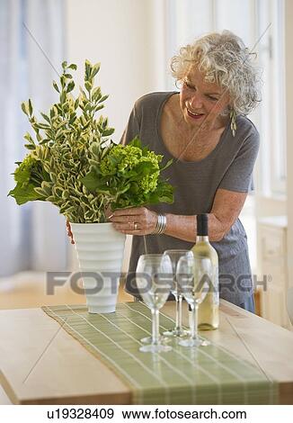 Woman arranging flowers in a vase View Large Photo Image Stock Photo - Woman arranging flowers in a vase. Fotosearch