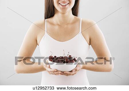 Stock Image - Woman holding a bowl of cherries. Fotosearch