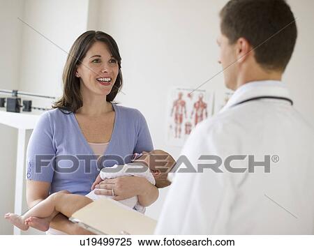 Stock Photography - Woman holding baby while talking to doctor. Fotosearch