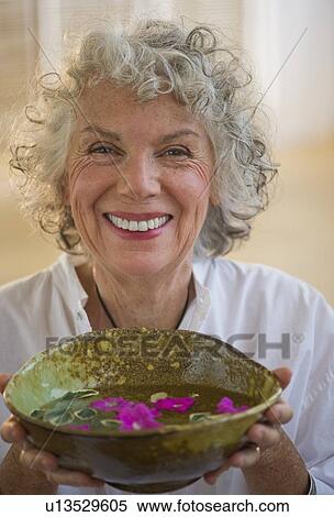 Stock Photography - Woman holding bowl of flower petals. Fotosearch
