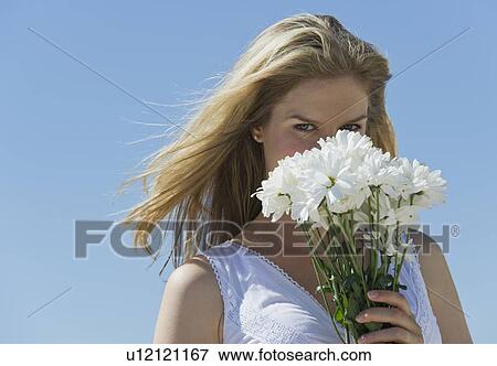 Stock Photo - Woman holding flowers in front of her face. Fotosearch