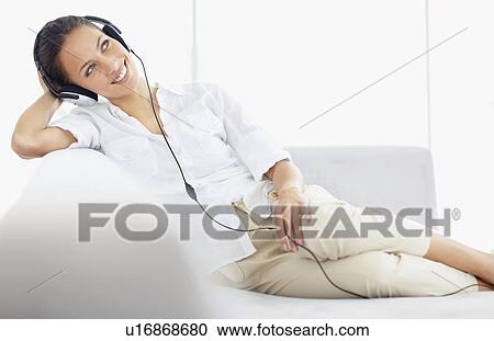 Stock Image - Woman listening to music on headphones. Fotosearch