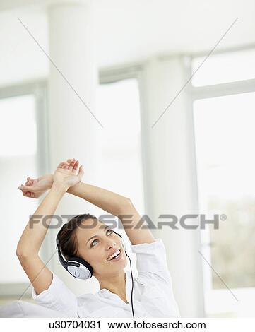Stock Image - Woman listening to music on headphones. Fotosearch