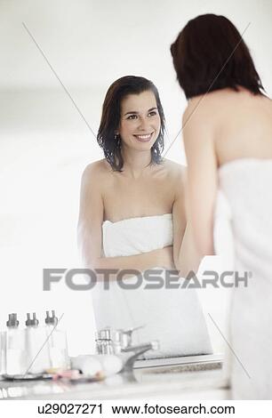 Stock Image - Woman looking at her reflection in mirror. Fotosearch
