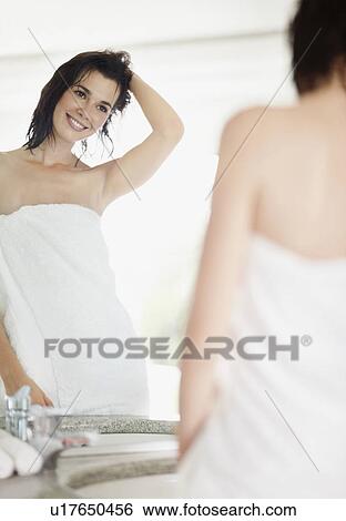 Stock Photograph - Woman looking at her reflection in mirror. Fotosearch