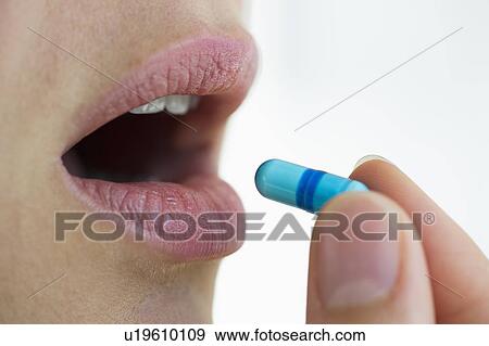 Stock Photo - Woman putting capsule in her mouth. Fotosearch