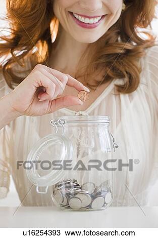 Woman putting penny in jar View Large Photo Image Stock Image - Woman putting penny in jar. Fotosearch