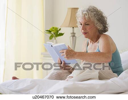 Stock Image - Woman reading in bed. Fotosearch