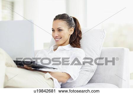 Woman relaxing on couch with laptop View Large Photo Image Stock Image - Woman relaxing on couch with laptop. Fotosearch