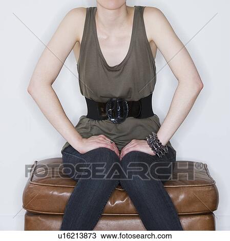 Stock Image - Woman sitting on ottoman. Fotosearch