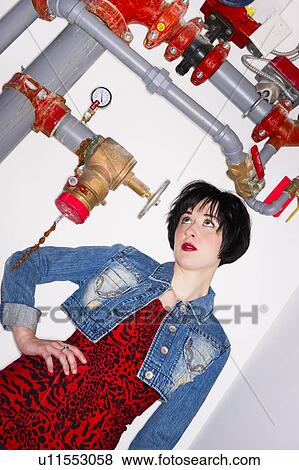Stock Photo - Woman standing beside pipes. Fotosearch