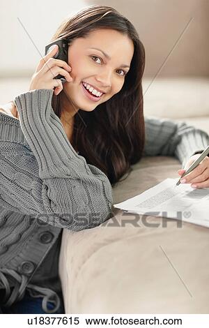 Stock Photography - Woman talking on phone while doing paperwork. Fotosearch