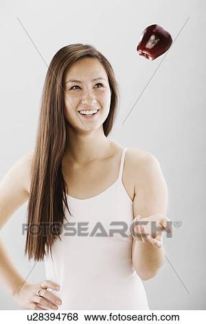 Stock Photo - Woman tossing a red apple. Fotosearch