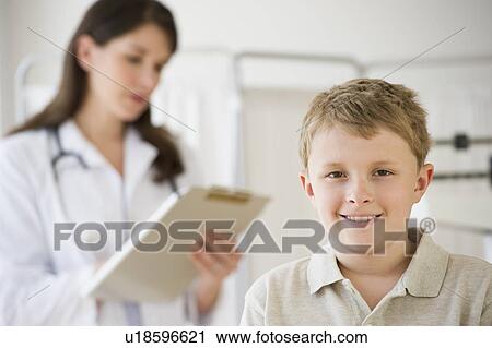 Stock Image - Young boy and doctor in examination room. Fotosearch