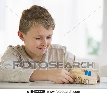 Stock Photo - Young boy looking at wooden train. Fotosearch