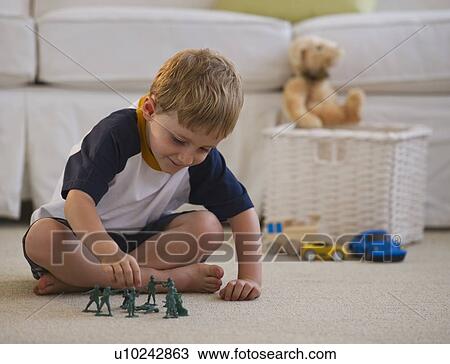 Stock Image - Young boy playing with toy soldiers. Fotosearch