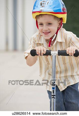 Young boy riding a scooter View Large Photo Image Picture - Young boy riding a scooter. Fotosearch