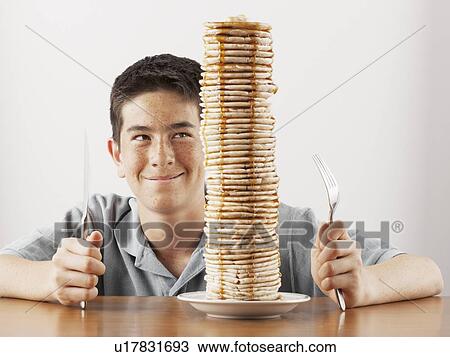 Young boy sitting behind a tall stack of pancakes View Large Photo Image Stock Image - Young boy sitting behind a tall stack of pancakes. Fotosearch