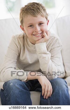 Young boy sitting on couch View Large Photo Image Picture - Young boy sitting on couch. Fotosearch