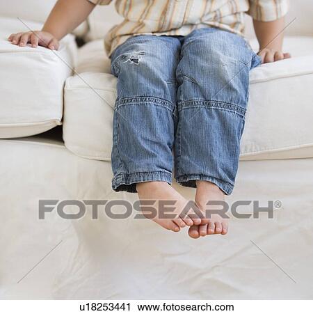 Stock Image - Young boy sitting on couch. Fotosearch