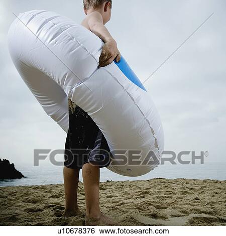 Young boy standing in an inflatable tube at the beach View Large Photo Image Stock Photograph - Young boy standing in an inflatable tube at the beach. Fotosearch