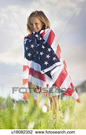 Stock Image - Young girl draped in American flag. Fotosearch